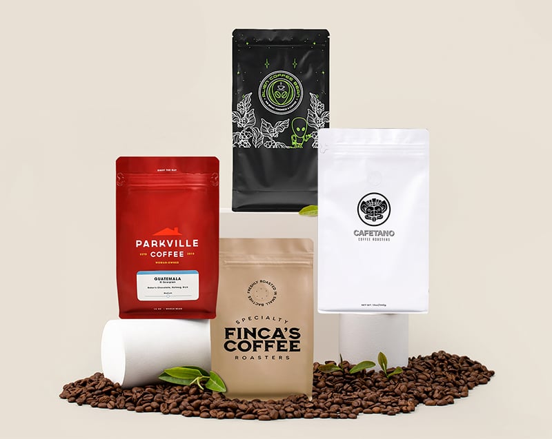 Four custom printed flat bottom coffee bags displayed with coffee beans