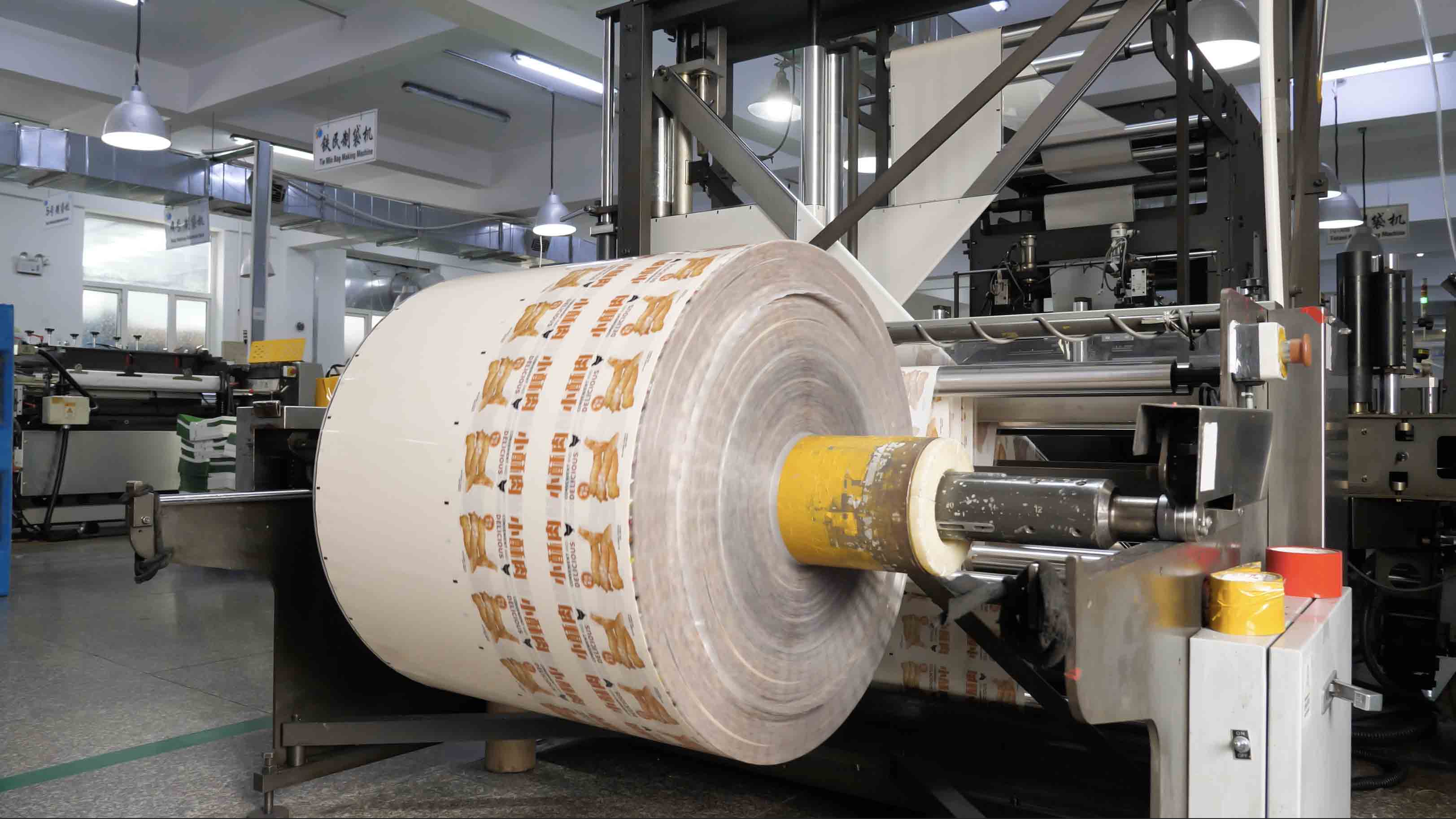 Printed packaging film roll positioned on converting equipment