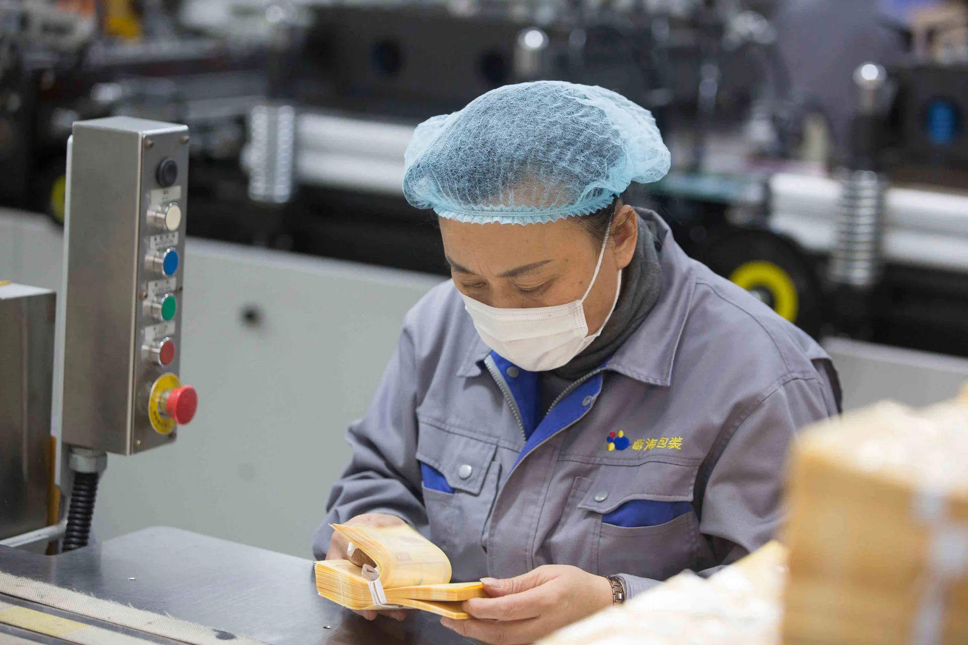 Packaging operator handling pouches beside production equipment